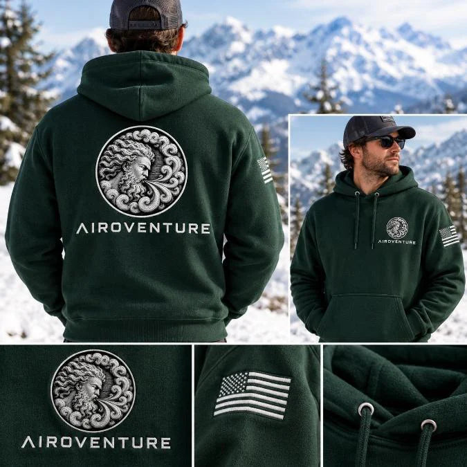 Forest green AiroVenture hoodie with the medallion and wordmark on the back, chest logo and sleeve flag, shown on a snowy mountain